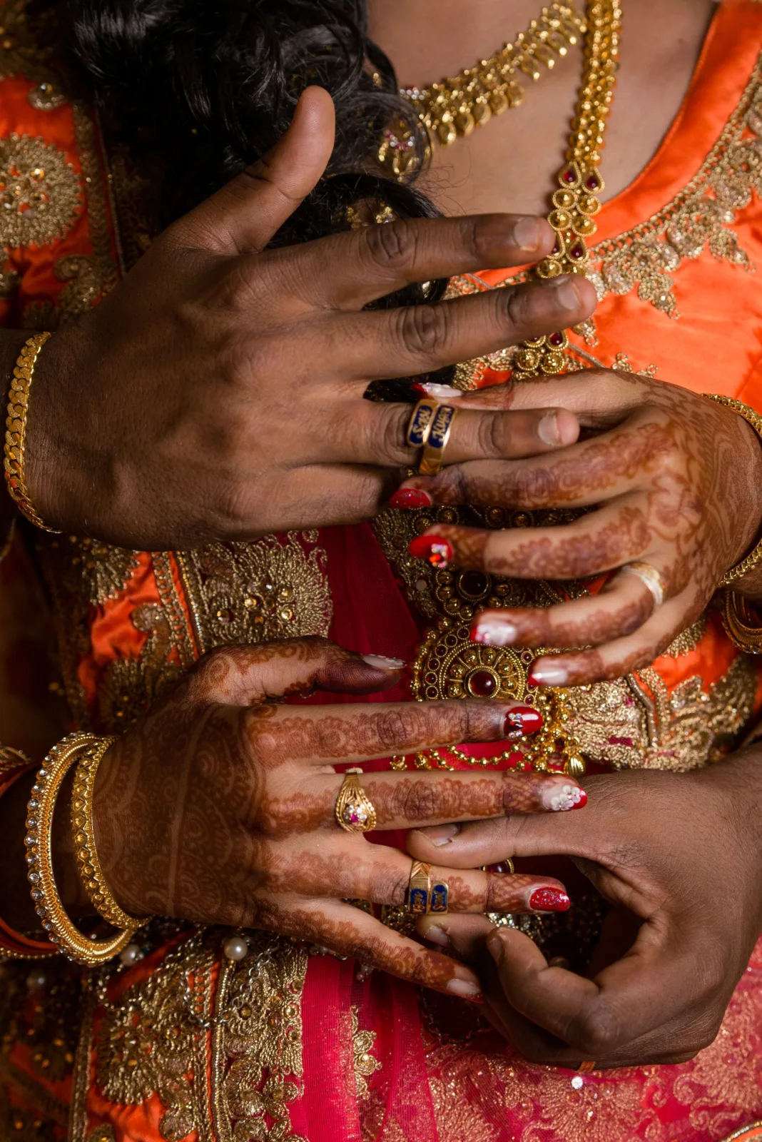 Close-up of the couple's hands with engagement rings, bangles and henna